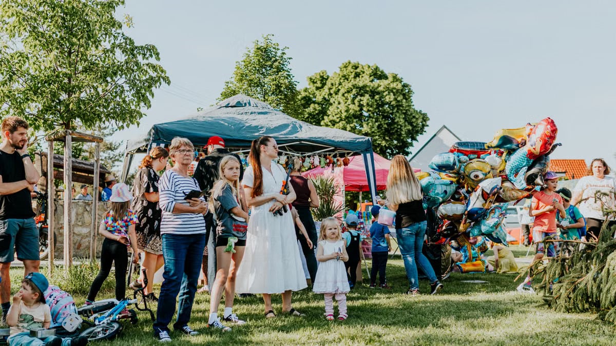A lively outdoor gathering with families enjoying balloons and a sunny day.
