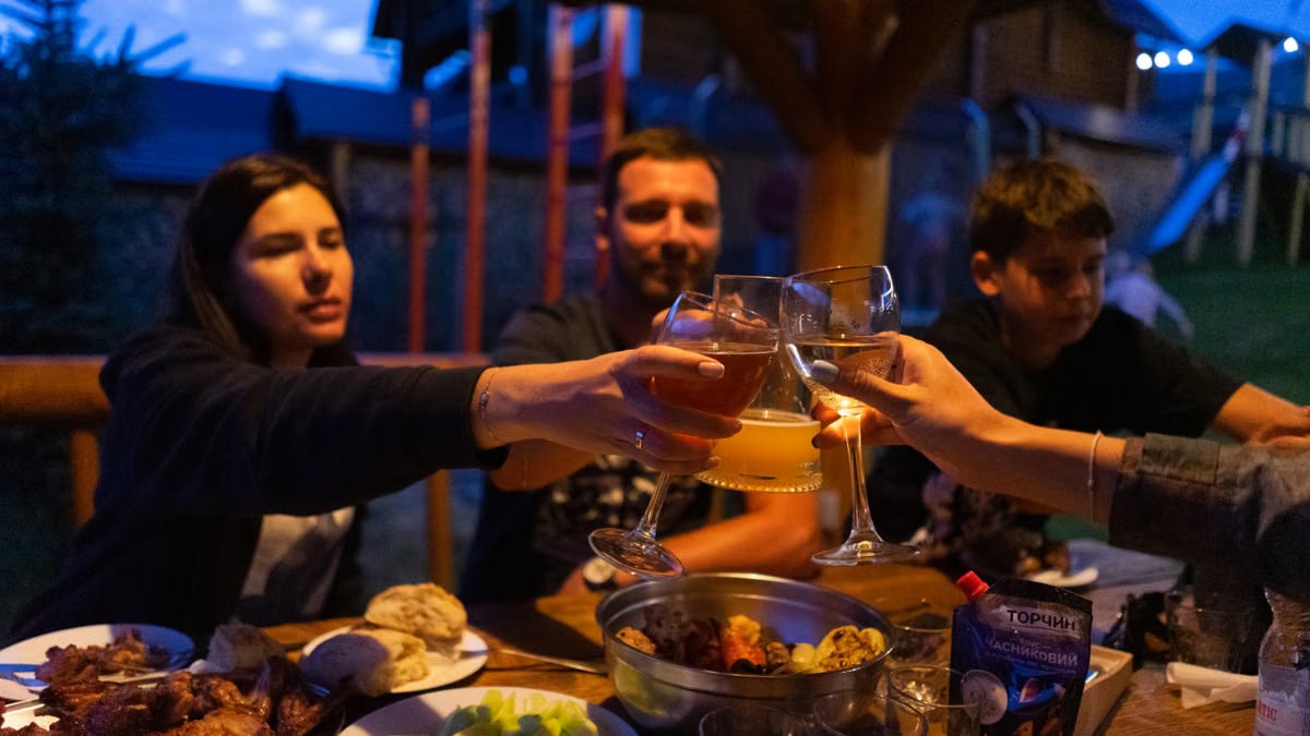 Friends clinking glasses at an outdoor dinner party, enjoying food and drinks.